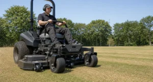 Operator bestuurt een zero-turn maaier met zichtbare maaibreedte-instelling over een droog gazon.