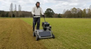 Man gebruikt een professionele verticuteermachine op een voetbalveld om het gras te verzorgen en onkruid te verwijderen.